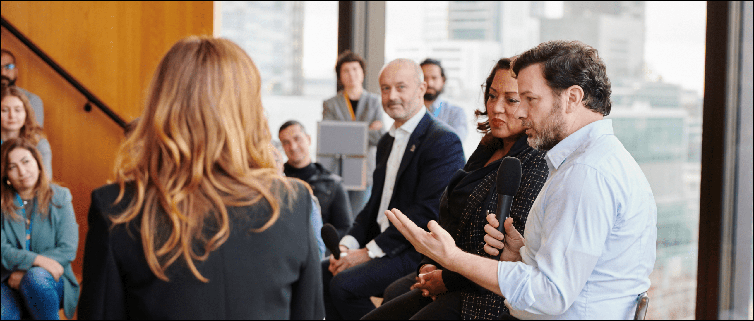 How to Build a Town Hall Framework for Success - A panel of speakers talk to an engaged audience. The image is focused on one speaker, with the adjacent professionals listening.