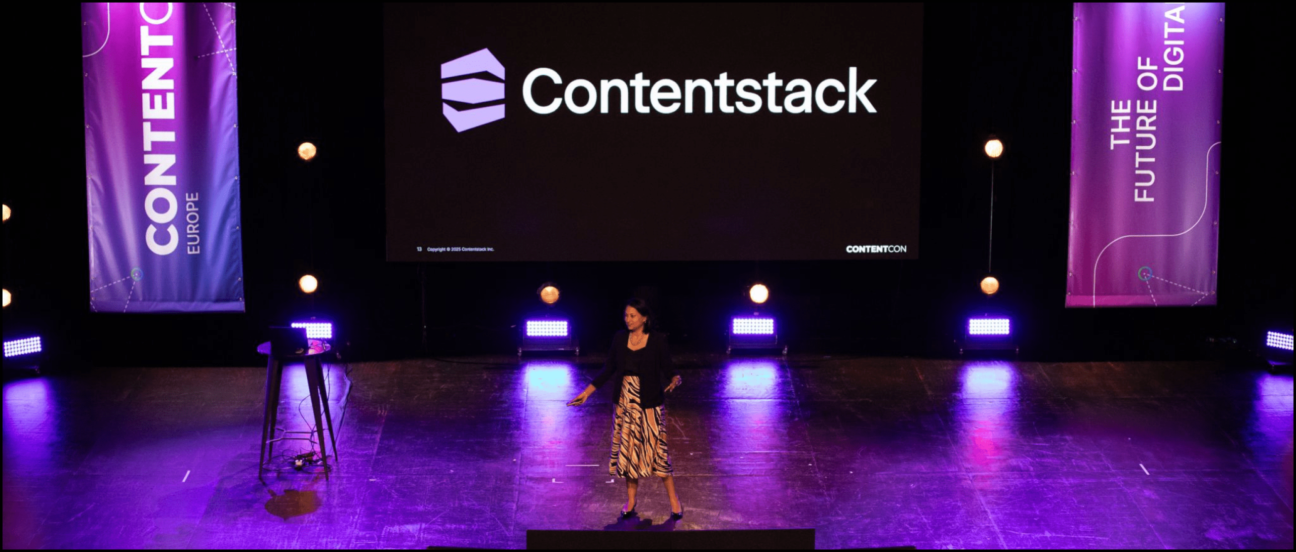 Event branding with Content stack. A presenter is filmed live on stage with purple lighting and custom banners either side of her